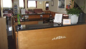 A hotel reception area with a wooden counter, a plant, and a sign indicating the hotel name. - Seattle Pacific Hotel (Seattle)