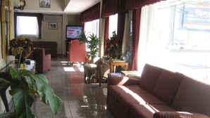 A hotel lobby with a red sofa, a coffee table, a TV, and a large potted plant. - Seattle Pacific Hotel (Seattle)