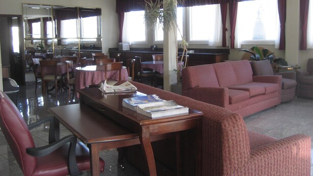 A hotel lobby with a dining area, a reception desk, and a seating area with a sofa and chairs. - Seattle Pacific Hotel (Seattle)
