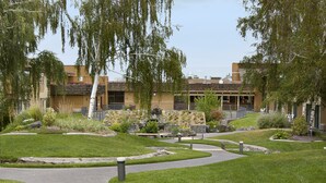 A landscaped courtyard with a winding path, a building with a flat roof, and a statue in the center. - Red Lion Hotel Kennewick Columbia Center (Kennewick)