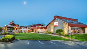 A hotel with a stone facade, a red roof, and a parking lot. - Red Lion Hotel Kennewick Columbia Center (Kennewick)