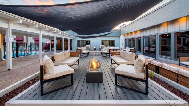 A covered outdoor seating area with a fire feature, lounge chairs, and a view of the pool. - Red Lion Hotel Kennewick Columbia Center (Kennewick)
