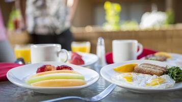 Mesa posta para o café da manhã, com pratos de comida, incluindo frutas e ovos.