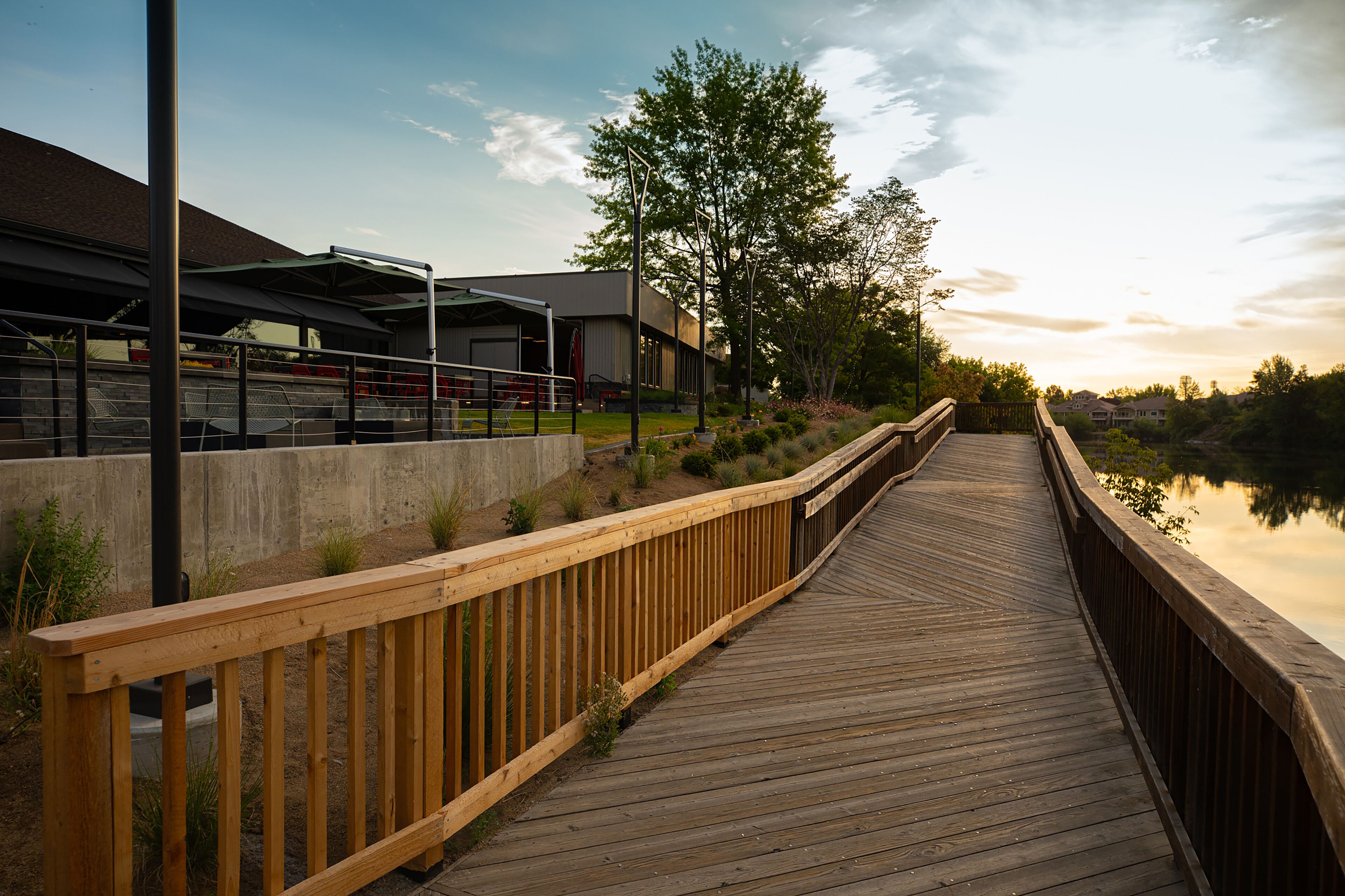 A wooden boardwalk leading to a modern building with a covered area.