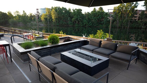 An outdoor patio with a seating area, a fire feature, and a view of a lake. - Ruby River Hotel Downtown Spokane (Spokane)