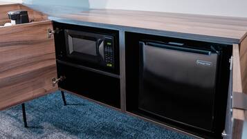 Une cuisine compacte équipée d’un four à micro-ondes et d’un réfrigérateur intégrés dans un meuble en bois.