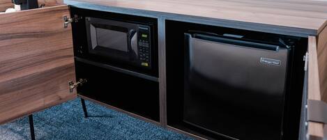 Une cuisine compacte équipée d’un four à micro-ondes et d’un réfrigérateur intégrés dans un meuble en bois.