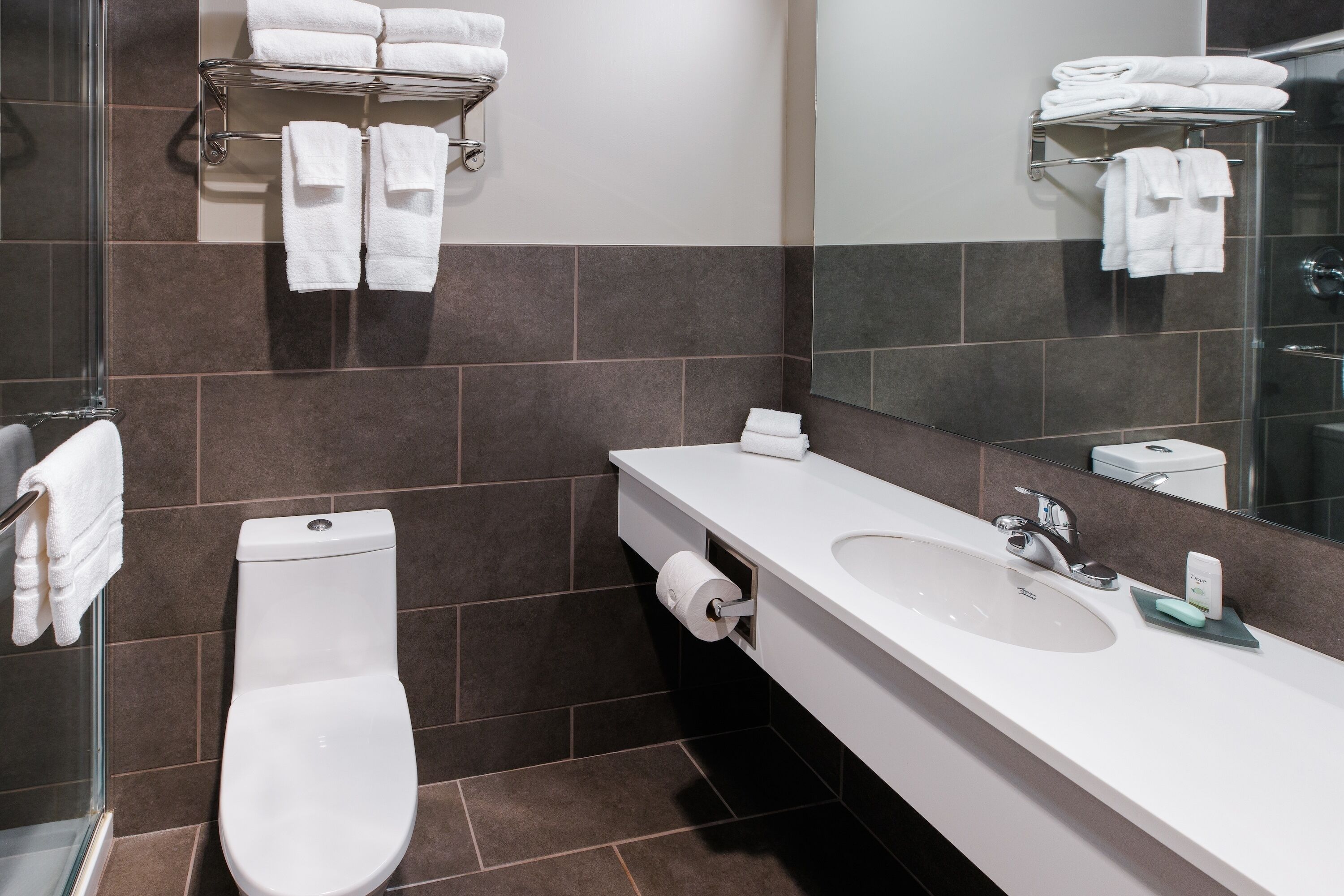 Un baño moderno con inodoro, lavamanos y cabina de ducha de vidrio.