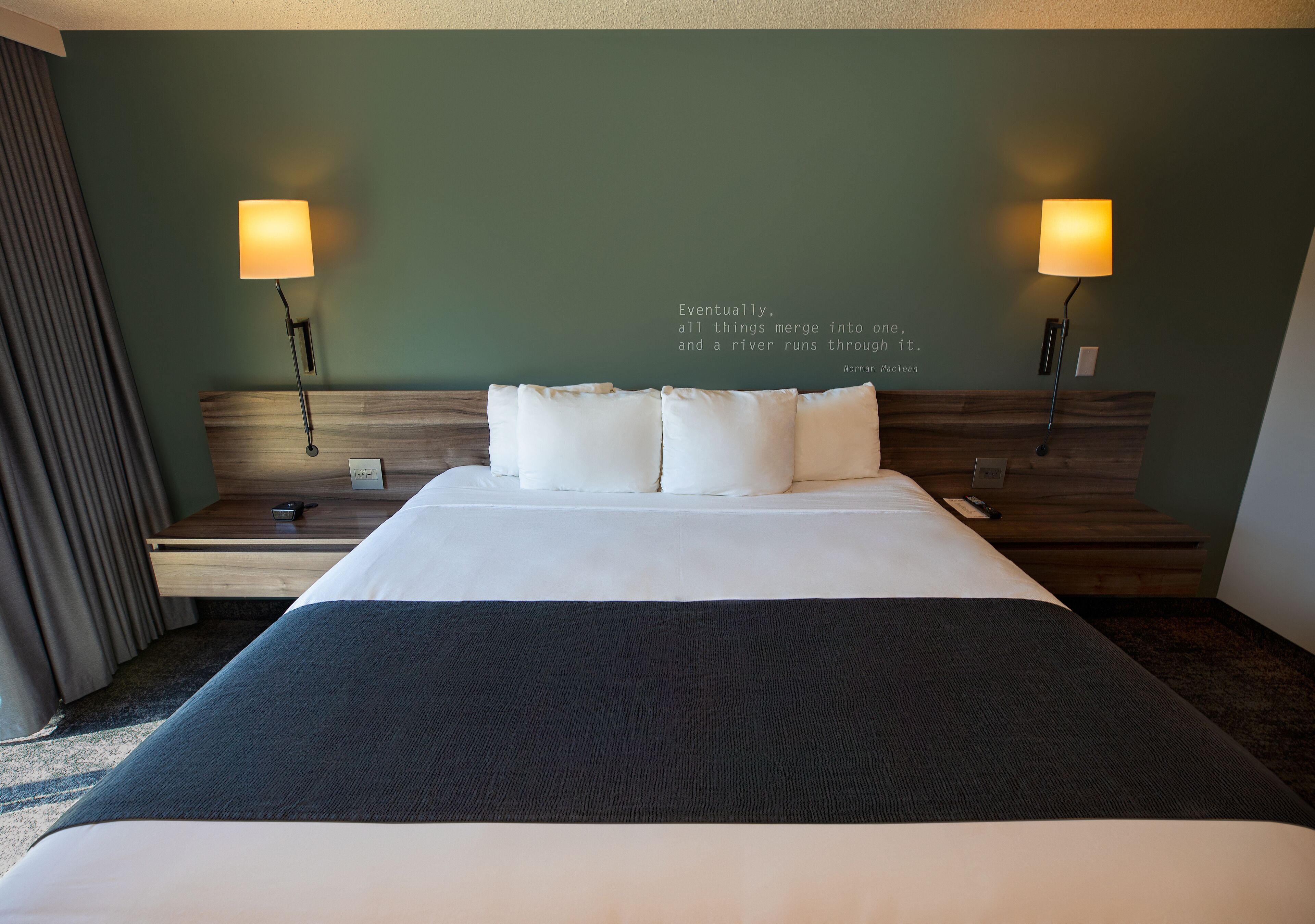 Een net opgemaakt bed met witte lakens en twee bedlampjes.