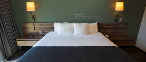 A neatly made bed with white linens and two bedside lamps.