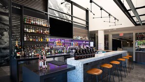 A modern bar with a marble countertop, multiple liquor bottles, and bar stools. - Ruby River Hotel Downtown Spokane (Spokane)