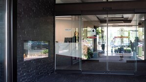 A modern building entrance with glass doors, a 'Stand Clear' sign, and an 'Automatic Door' sign.