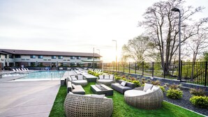 A poolside area with outdoor seating and a building in the background.