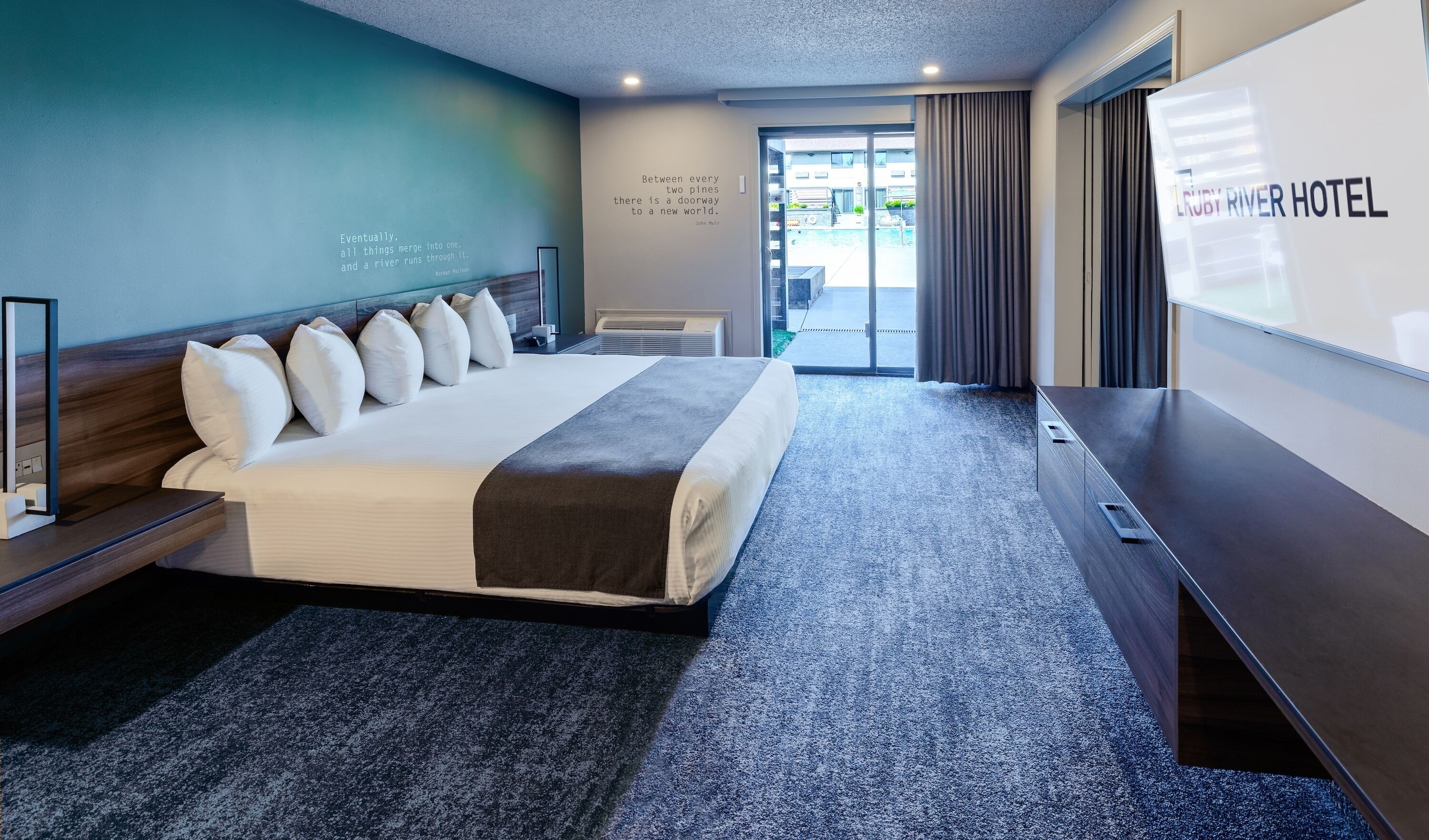 Habitación de hotel con una cama grande, televisión, escritorio y vistas al exterior.