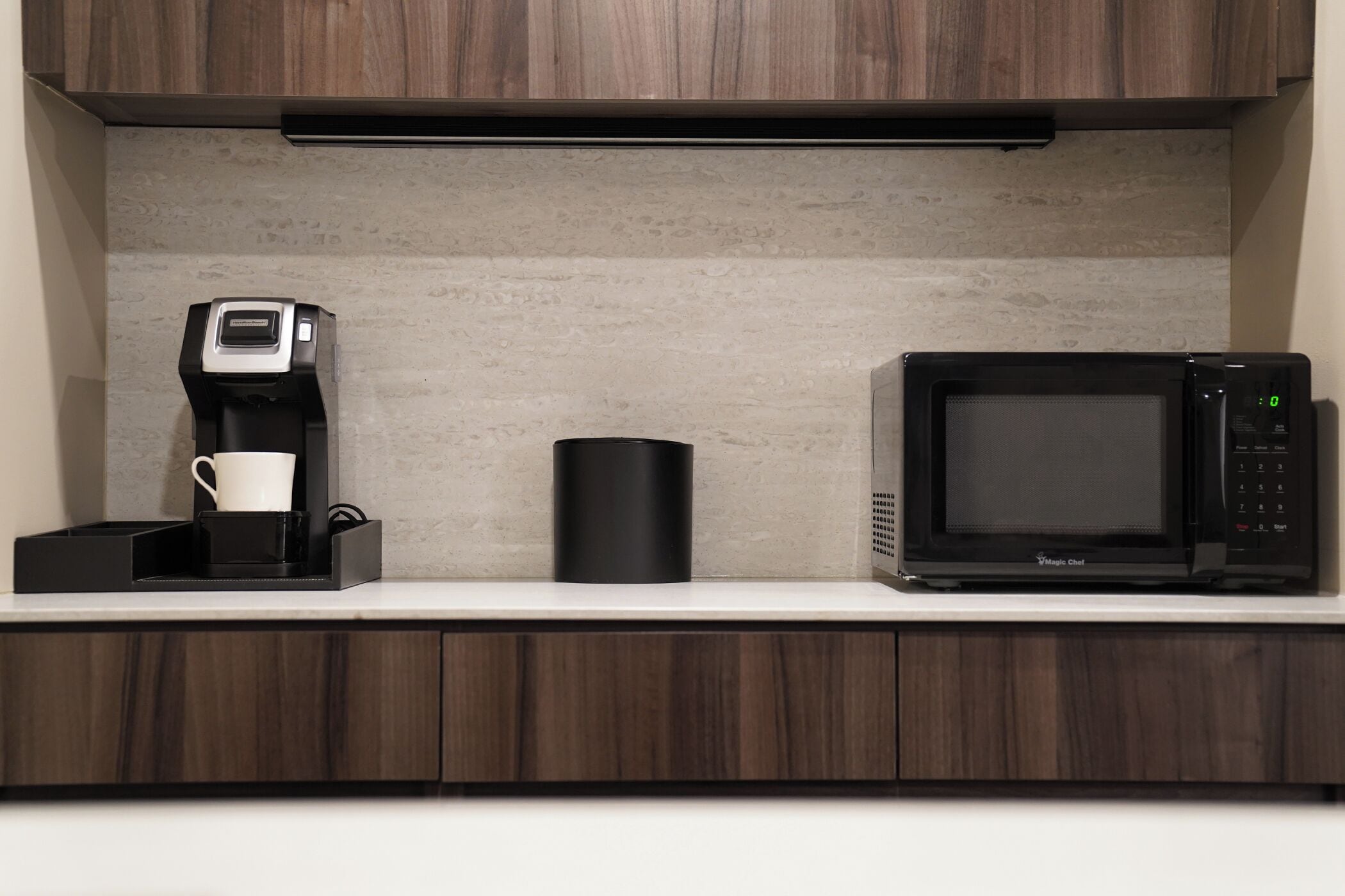 A kitchen with a coffee maker, a microwave, and a black container on the countertop.