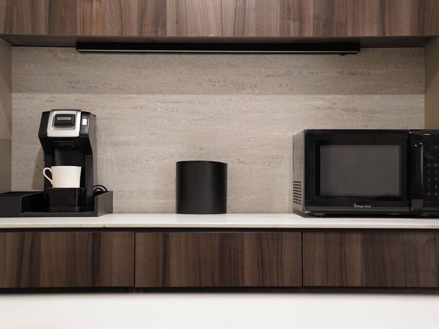 A kitchen with a coffee maker, a microwave, and a black container on the countertop.