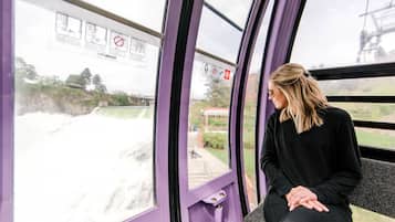 A person seated by a window with a view of a water body and a building in the background.