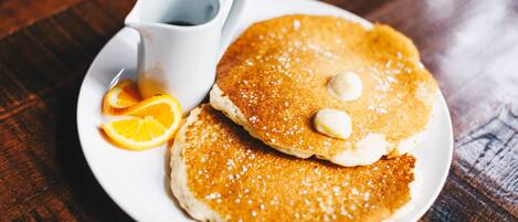Dos tortitas en un plato con almíbar y una taza de café.