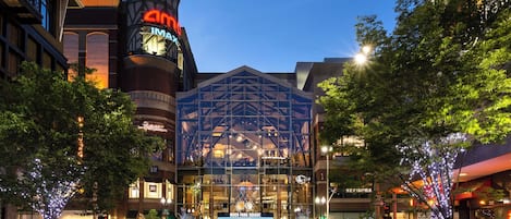 A multi-story building with a prominent IMAX cinema sign, surrounded by trees and various storefronts.