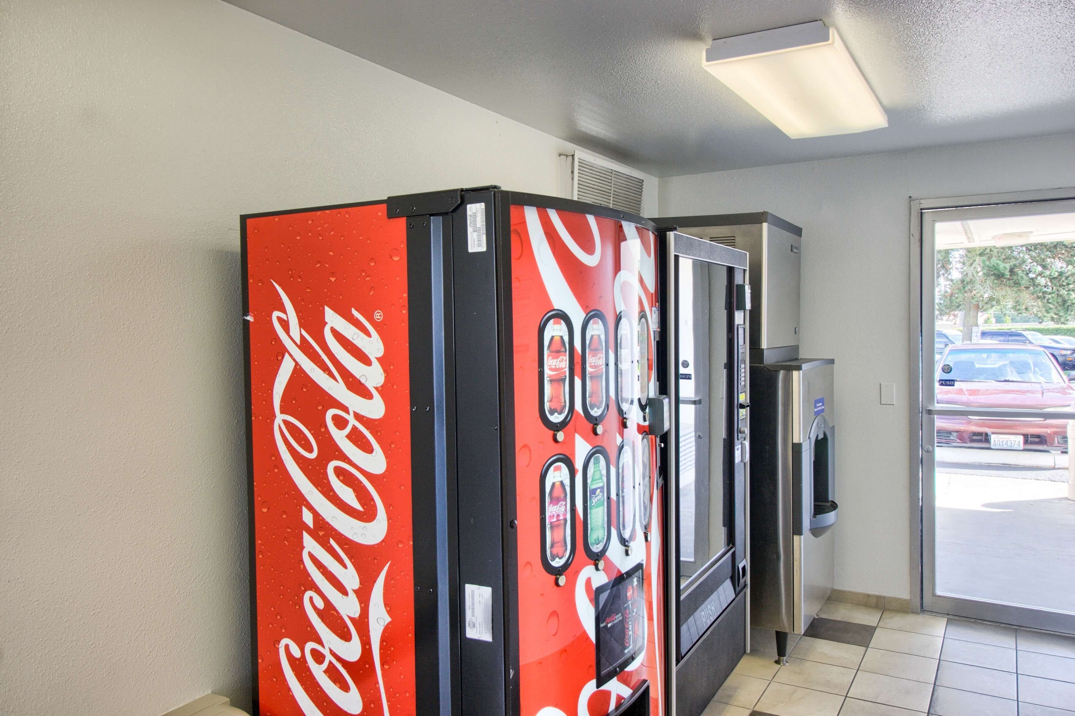 A vending machine area with a Coca-Cola branded machine and a refrigerator.