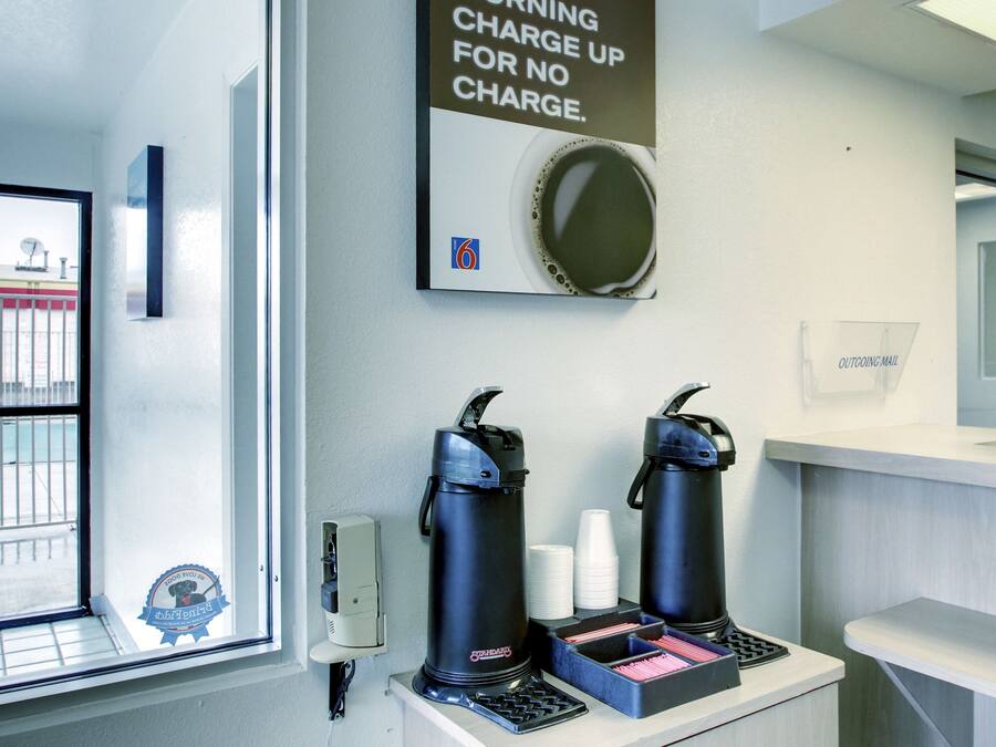Ein Kaffee-Bereich mit zwei Kaffeeautomaten, einem Schild mit dem Hinweis auf kostenlose Lademöglichkeiten und einem Schild für ausgehende Post.