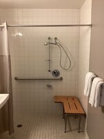Un área de ducha con una barra de apoyo, un banco y un perchero para toallas.
