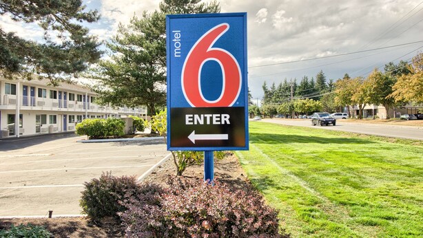 A motel sign with the number 6 and an arrow pointing left, indicating the entrance direction.