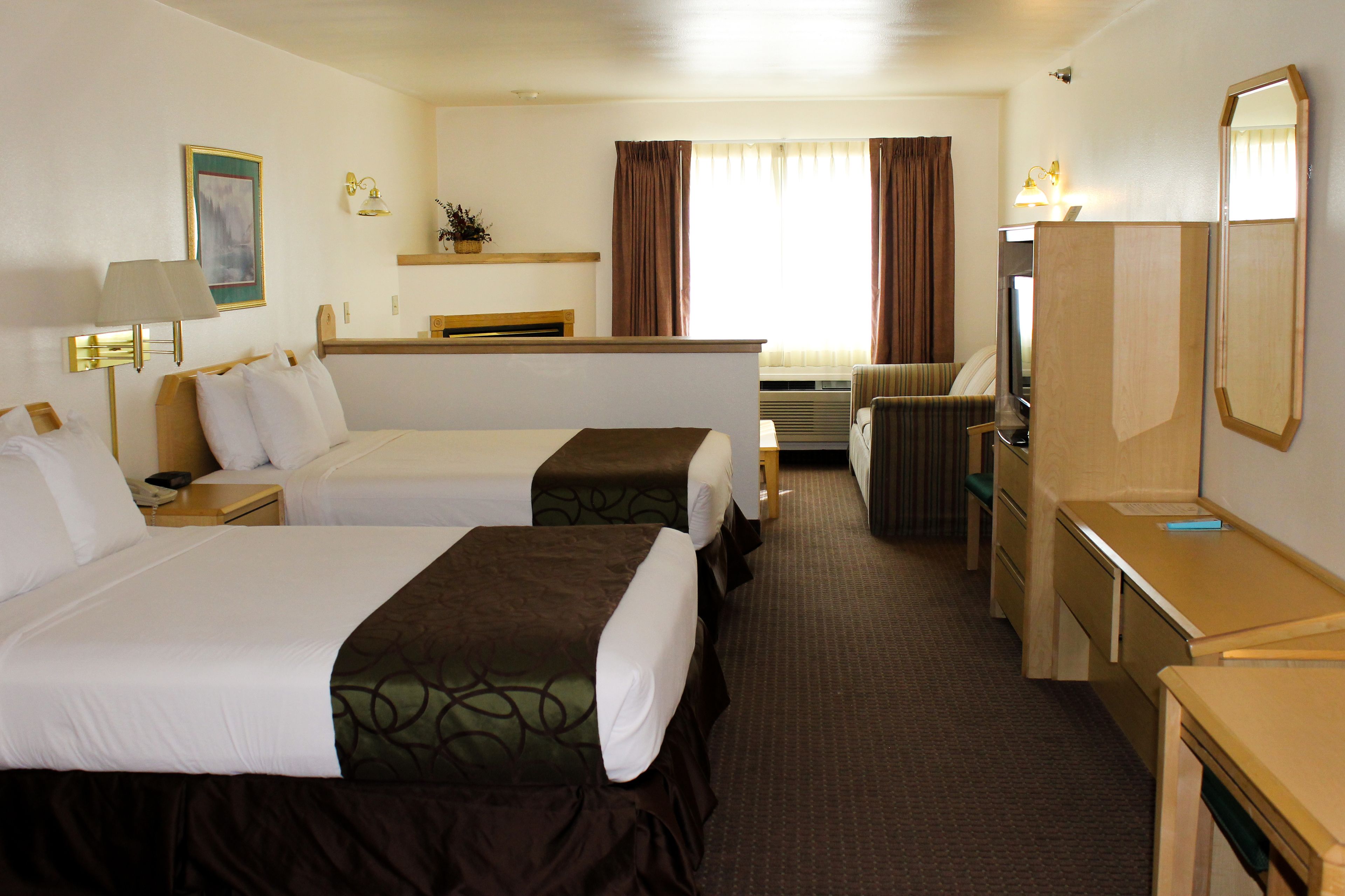 Une chambre d’hôtel avec deux lits, un bureau, une chaise, une télévision et un miroir.