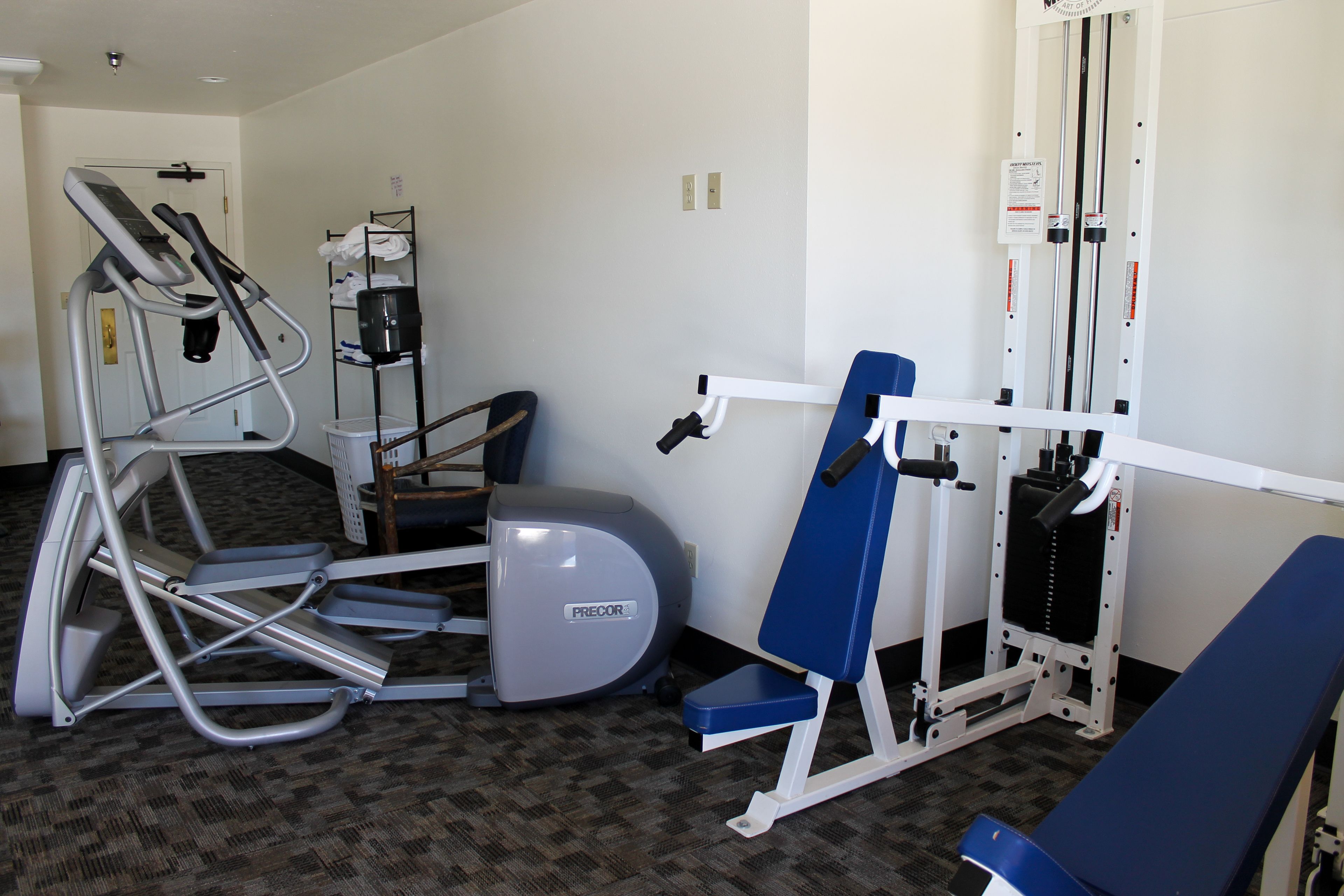 A fitness center with treadmills, an elliptical, a bench, and a weight machine.