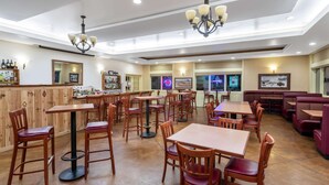 A restaurant with wooden tables and chairs, a bar area, and a seating section with cushioned booths. - Inn at Lander, Travelodge by Wyndham (Lander)
