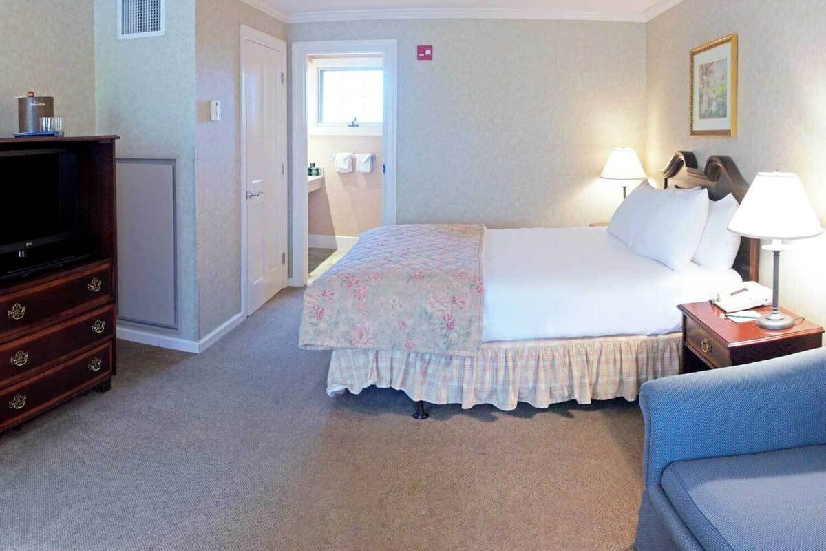 A hotel room with a bed, a TV, a desk, and a chair.