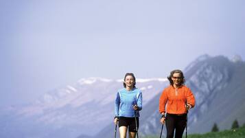 Two people hiking in a grassy field with a mountain in the background.