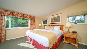 A hotel room with a large bed, two bedside lamps, a nightstand, and a window with curtains.