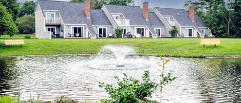 Une rangée de maisons modernes, avec un bassin central et des bancs.