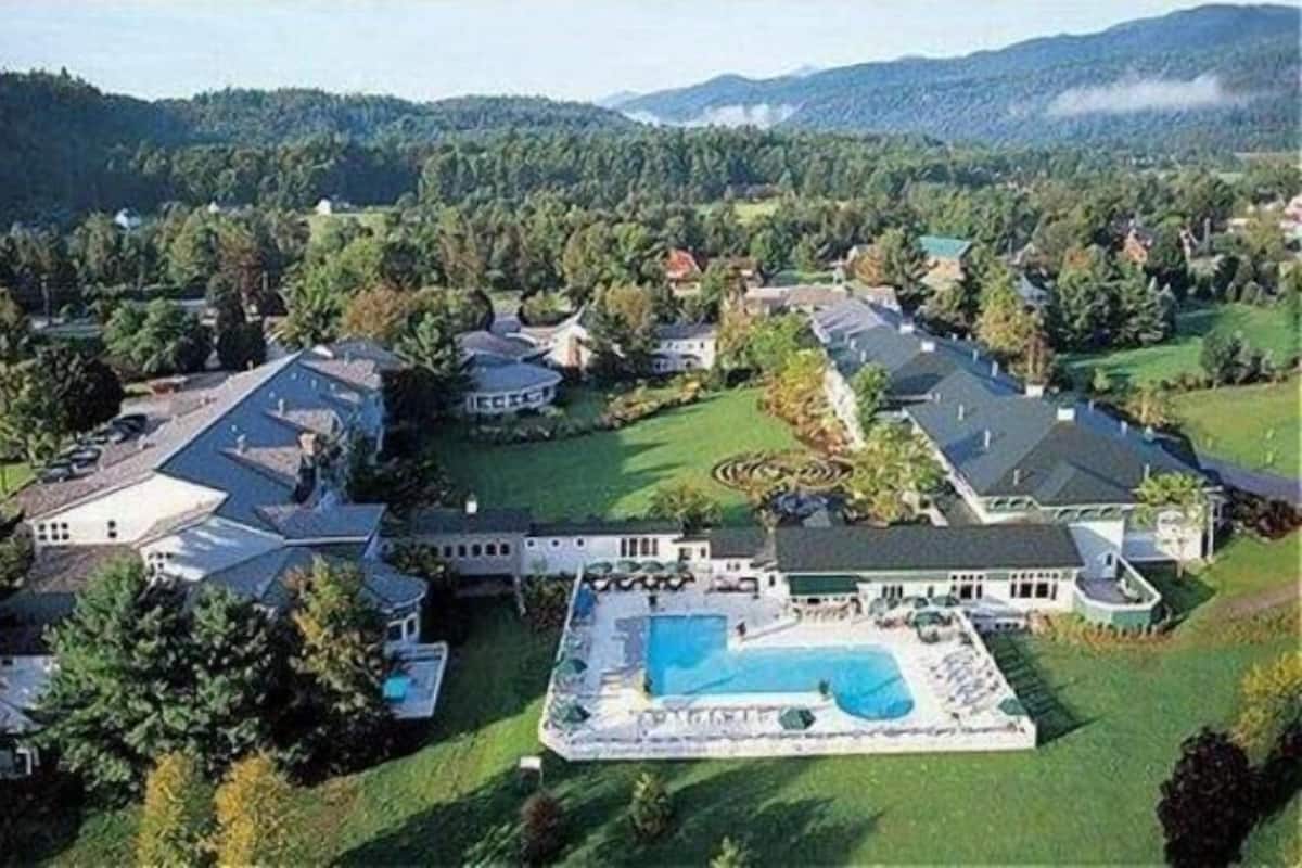 A large estate with multiple buildings, a swimming pool, and surrounding greenery.
