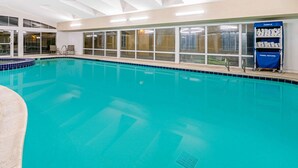 An indoor swimming pool with clear blue water, a towel return cart, and a view of the outside through large windows. - La Quinta Inn & Suites by Wyndham Salt Lake City Airport (Salt Lake City)