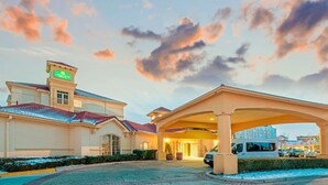 A hotel entrance with a covered driveway, a sign indicating 'Quinta', and a van parked outside. - La Quinta Inn & Suites by Wyndham Salt Lake City Airport (Salt Lake City)