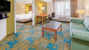 A hotel room with a bed, a desk, a green sofa, and a television. - La Quinta Inn & Suites by Wyndham Salt Lake City Airport (Salt Lake City)