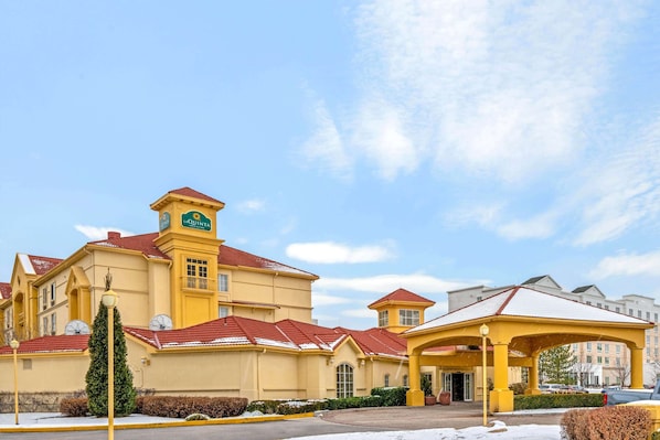 Quinta's central tower features a clock and a sign, surrounded by a covered walkway and parking area.
