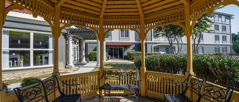 Un espacio de estar al aire libre cubierto con dos bancos y una estructura de pérgola.