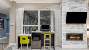 Een moderne woonkamer met een open haard, een bureau met een computer en twee stoelen.
