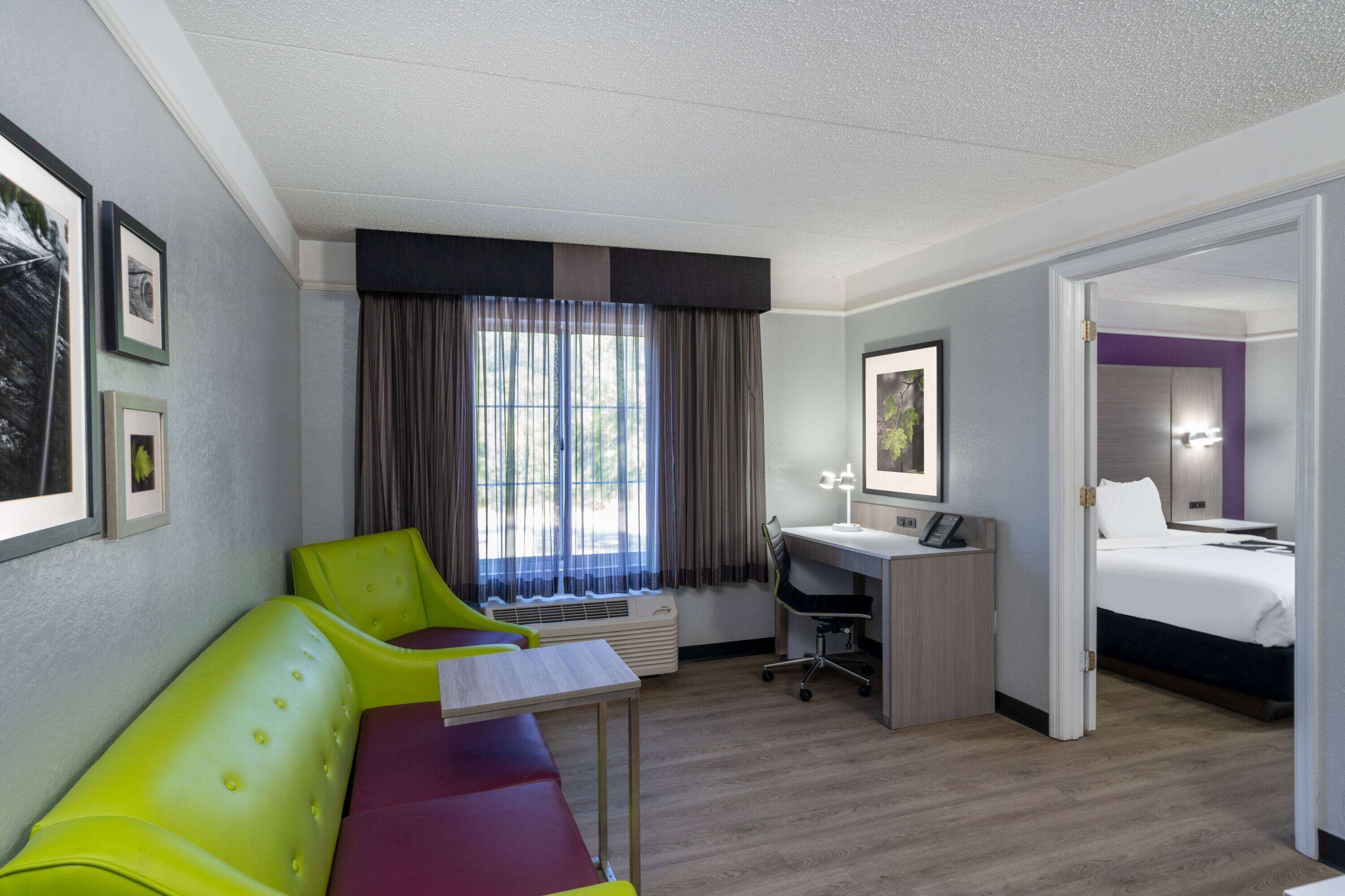 Een hotelkamer met een bed, een bureau, een stoel en een bank.