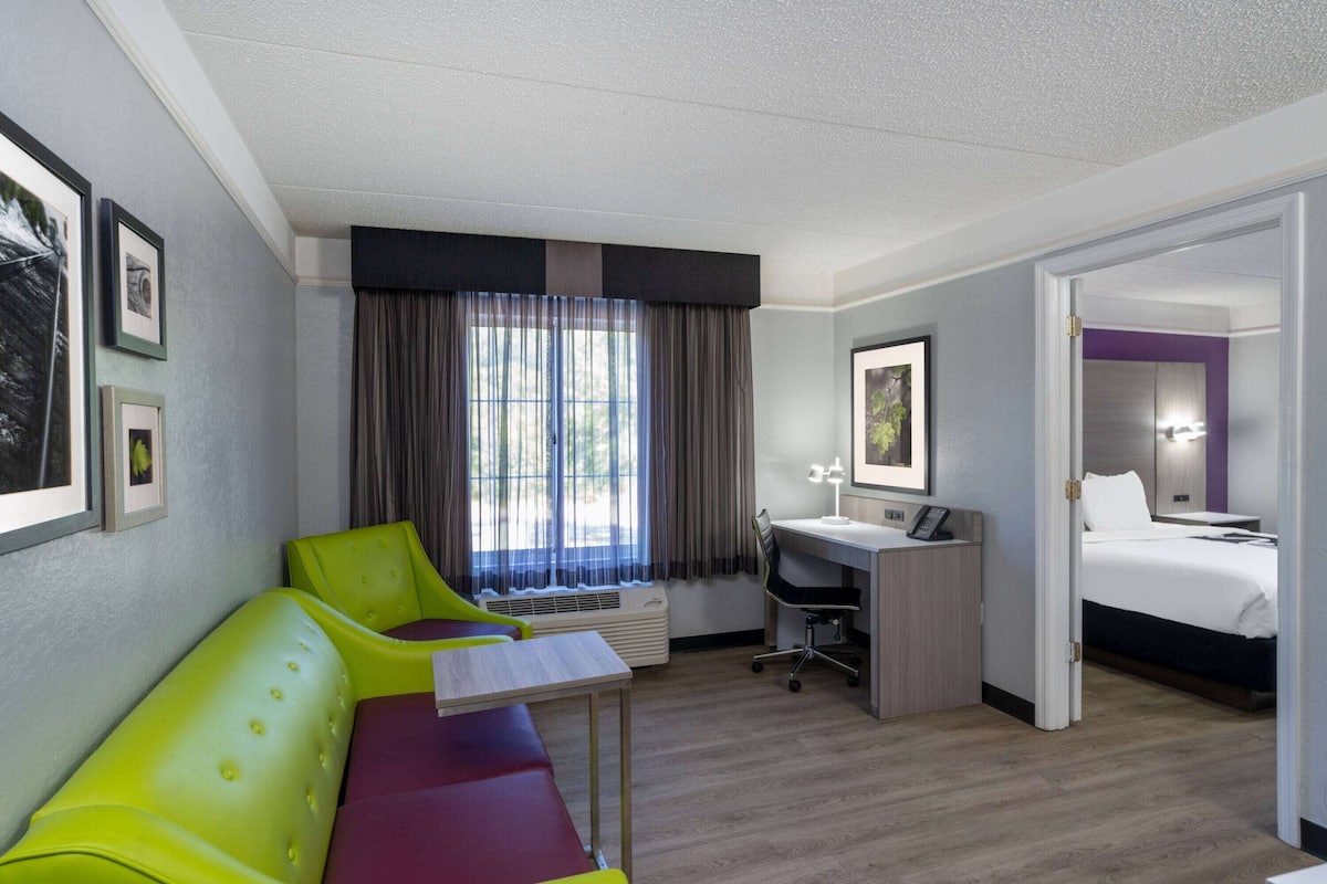 Una habitación de hotel con cama, escritorio, silla y sofá.