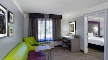 A hotel room with a bed, a desk, a chair, and a couch.