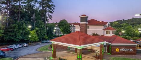 A hotel with a red-roofed pavilion, a parking area, and a building with a sign reading "La Quinta".
