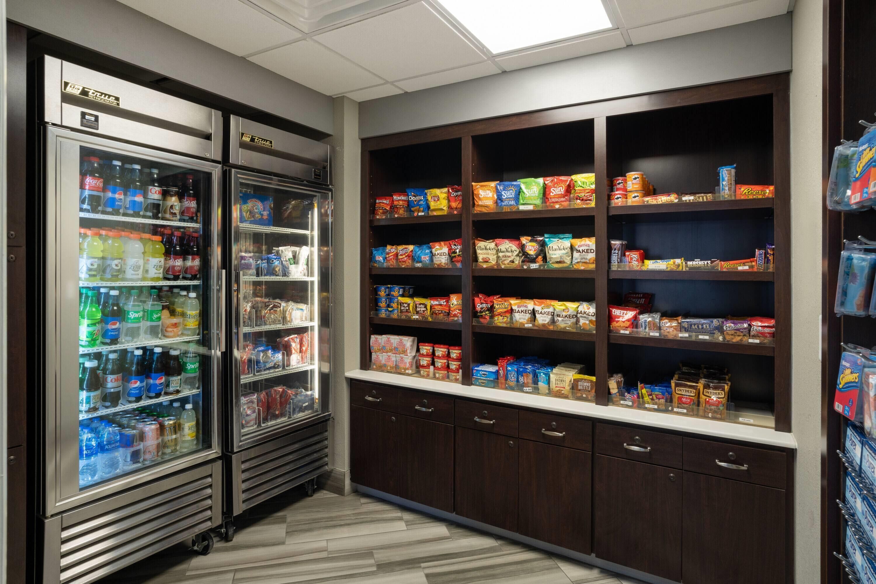 A snack and beverage area with refrigerated drink dispensers and shelves stocked with various snacks and packaged goods.