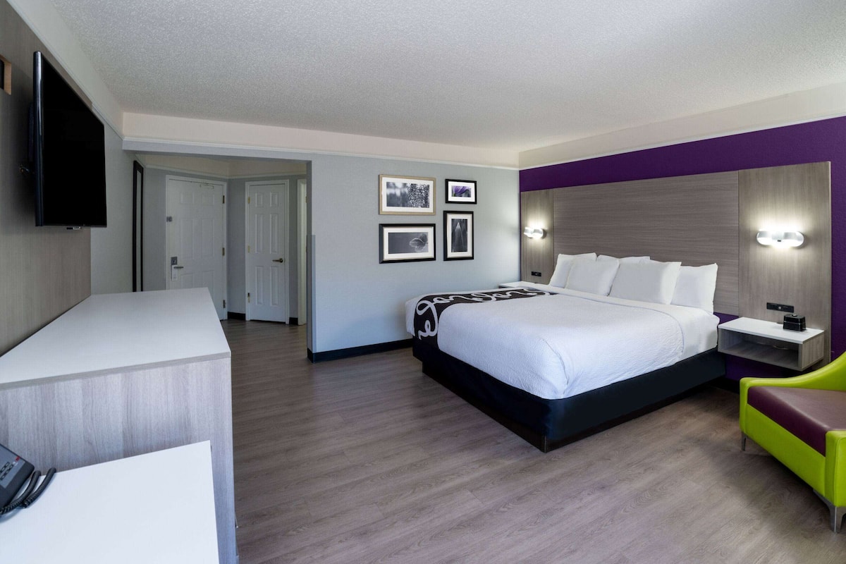 Una habitación de hotel con cama, mesita de noche, televisor y escritorio con teléfono.