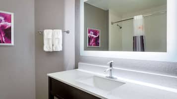 Un bany amb un lavabo blanc, un mirall gran i un suport de tovalloles amb dues tovalloles blanques.