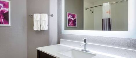 A bathroom with a white sink, a large mirror, and a towel rack with two white towels.