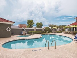 Una piscina al aire libre, sombrillas, sillones reclinables de piscina